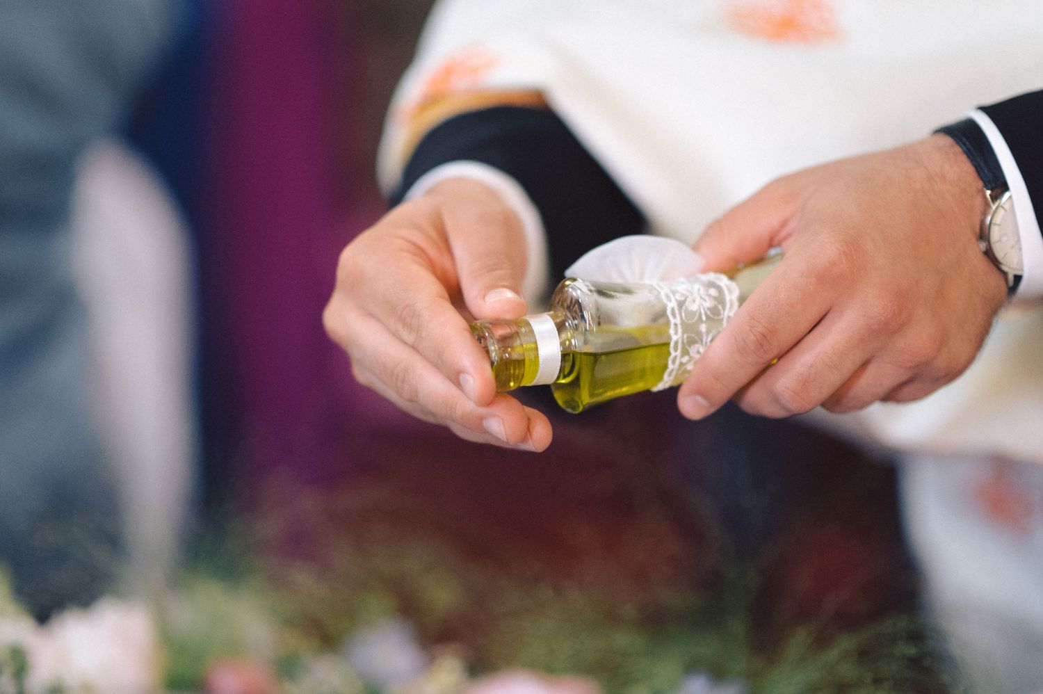 Close-up shot of hands pouring holy oil during a religious ceremony.
