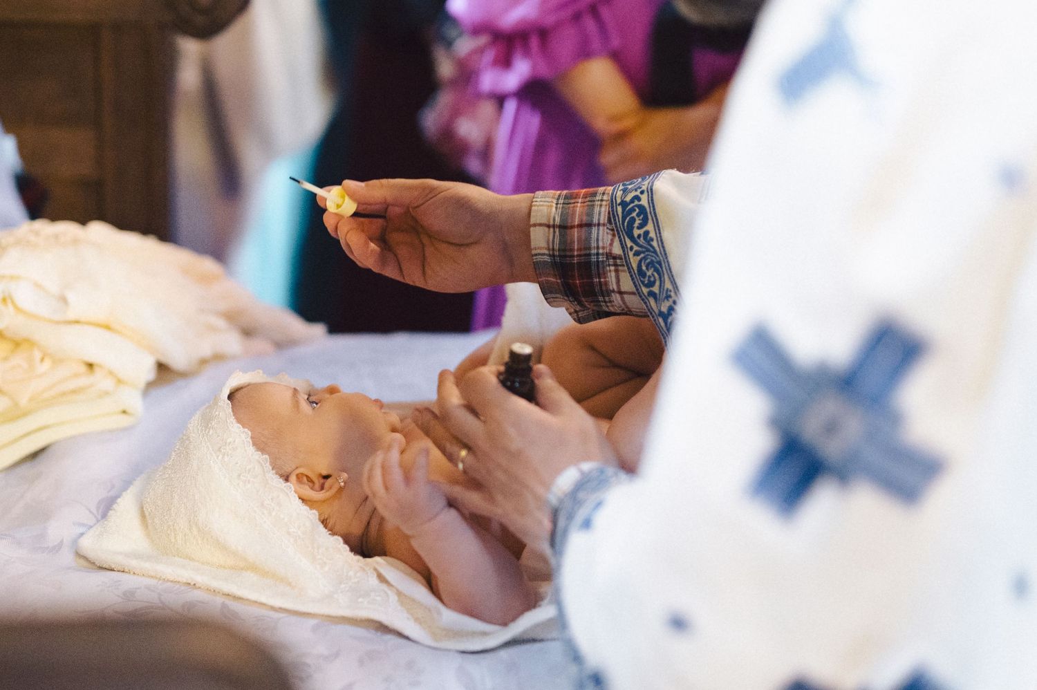Baby receiving care during medical examination while wrapped in white blanket.