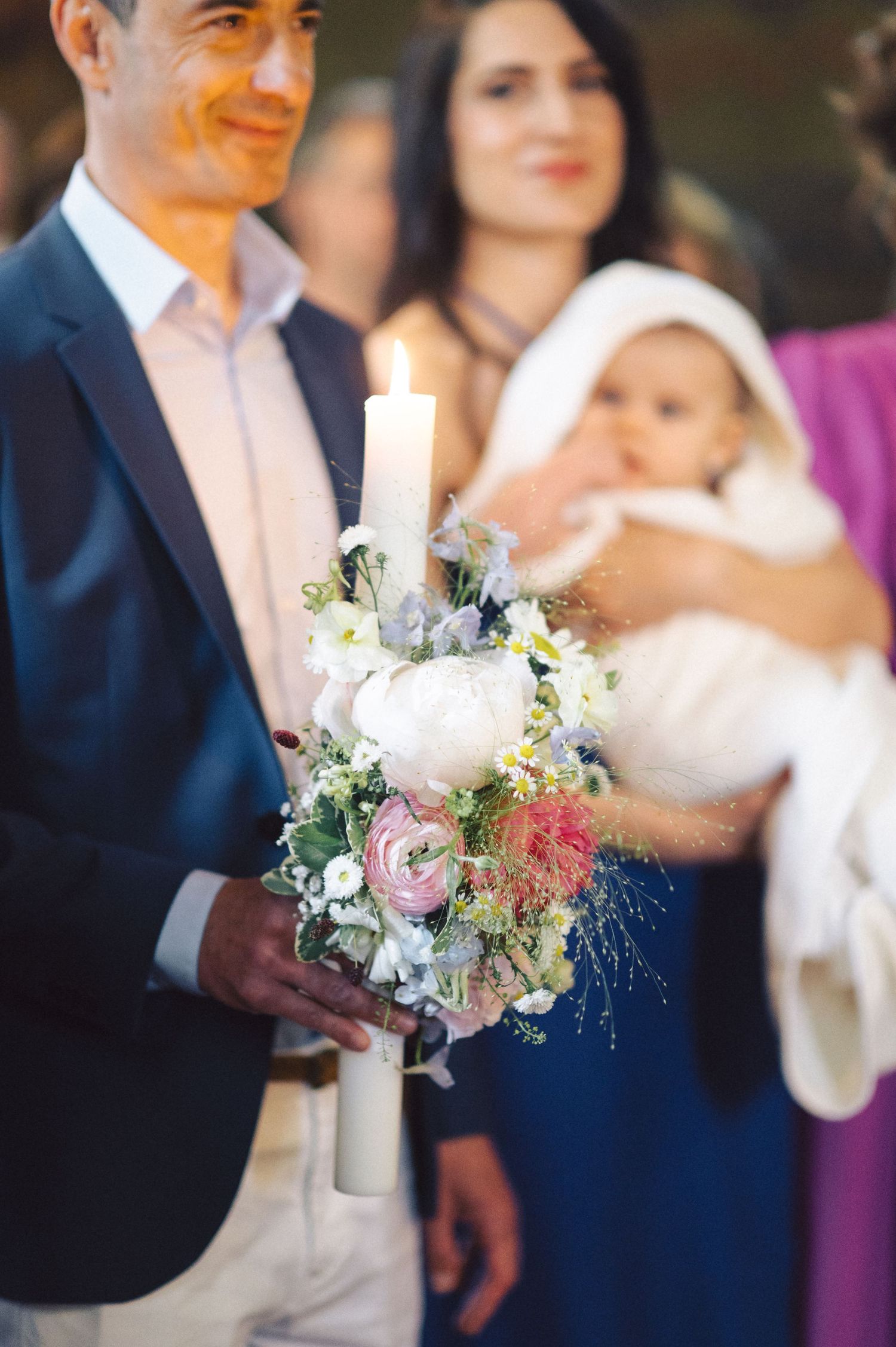 An elegant floral arrangement with white and pink flowers is held during a baptism ceremony.