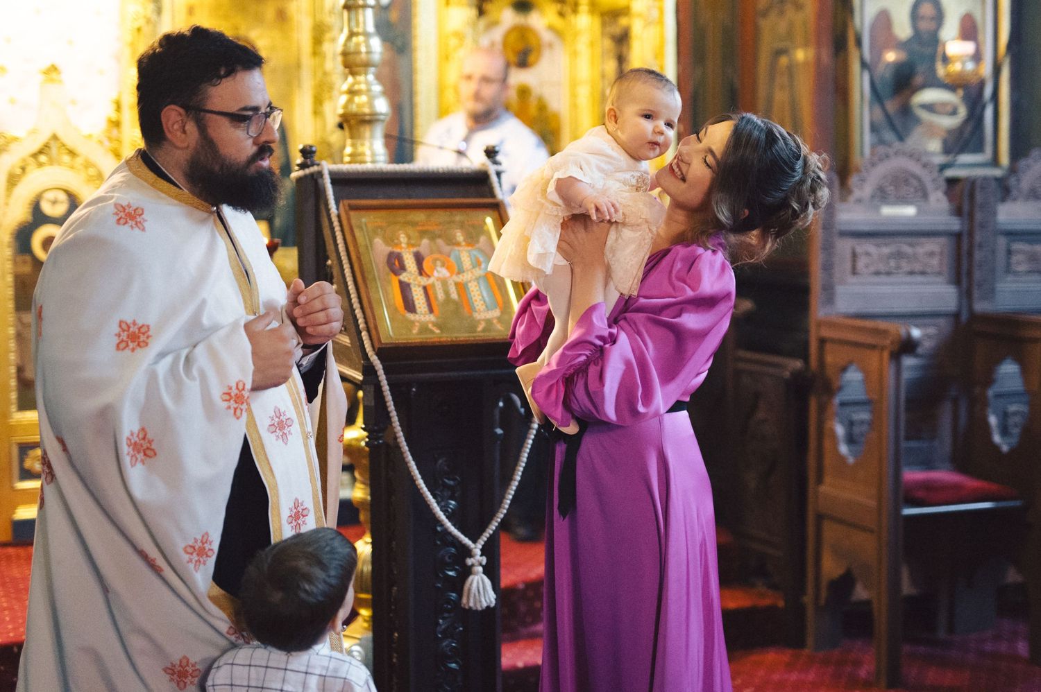 A religious ceremony takes place in an ornate church with gilded decorations and icons.