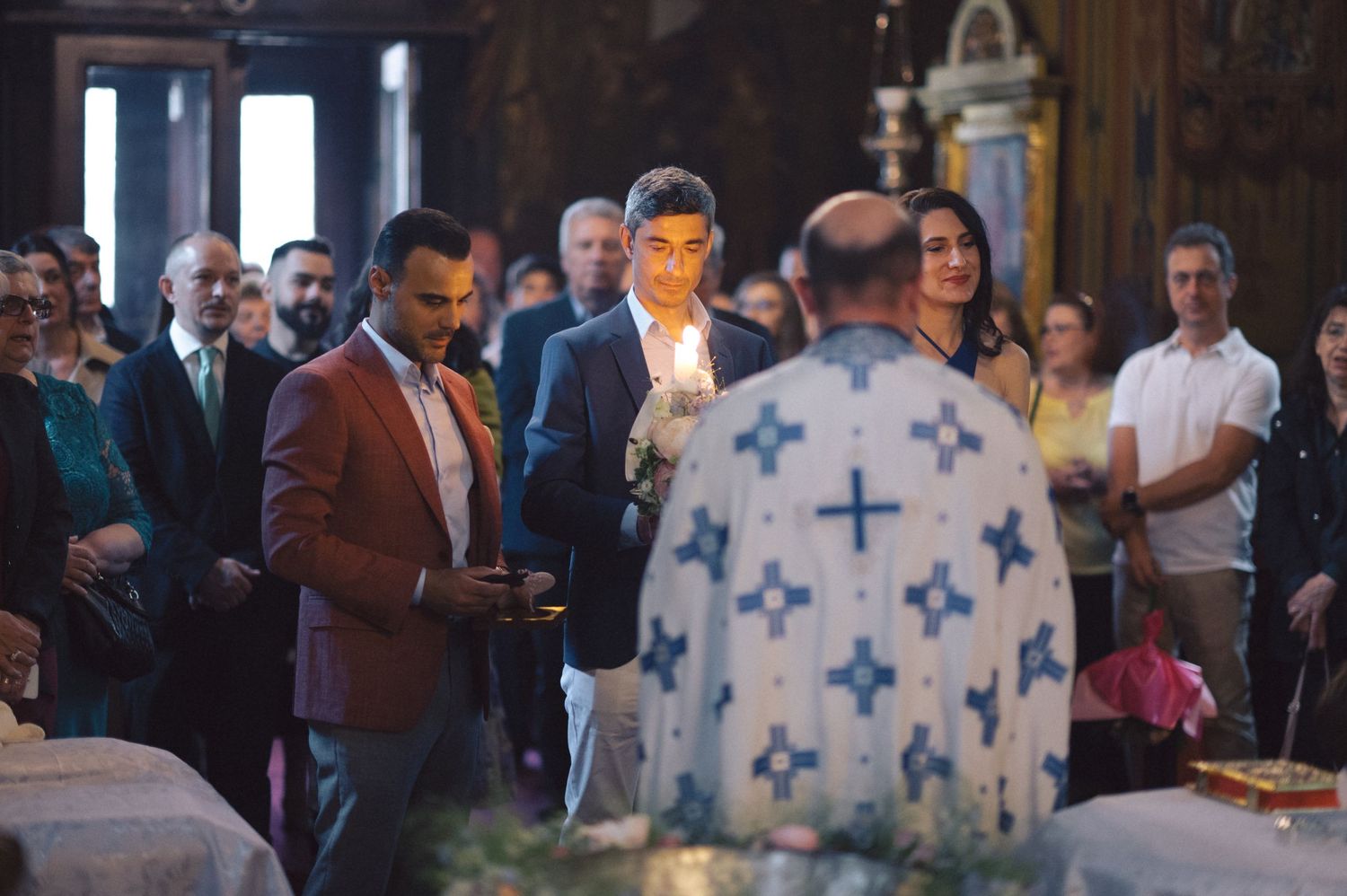 A religious ceremony in a church with an Orthodox priest wearing traditional blue and white vestments performing a ritual.