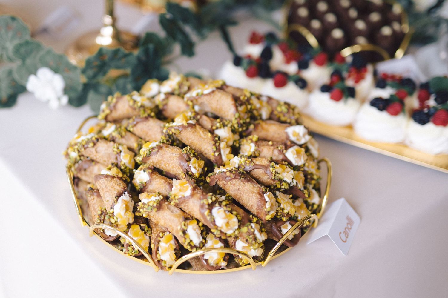 A decorative platter of holiday cookies with nuts, sprinkles and confections arranged on a white tablecloth.