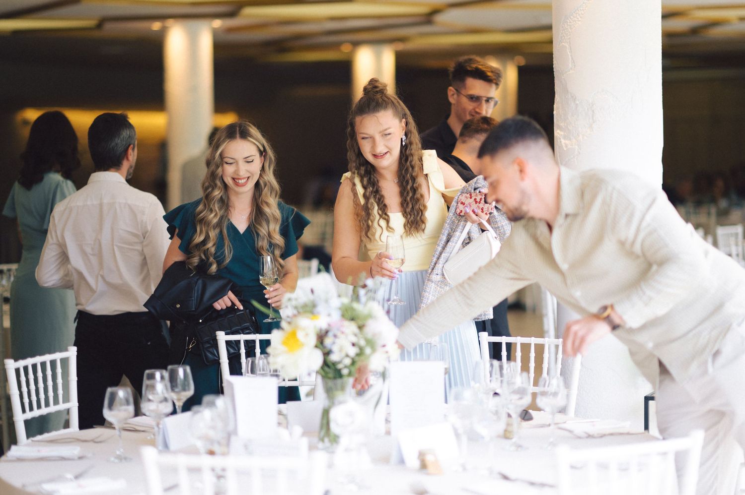 Event guests interacting at an elegant table setting with white floral centerpieces.