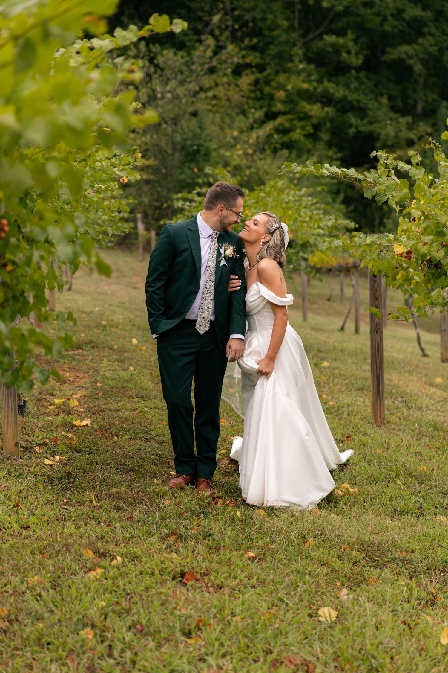 A couple shares a romantic moment while walking through a scenic vineyard on their wedding day.