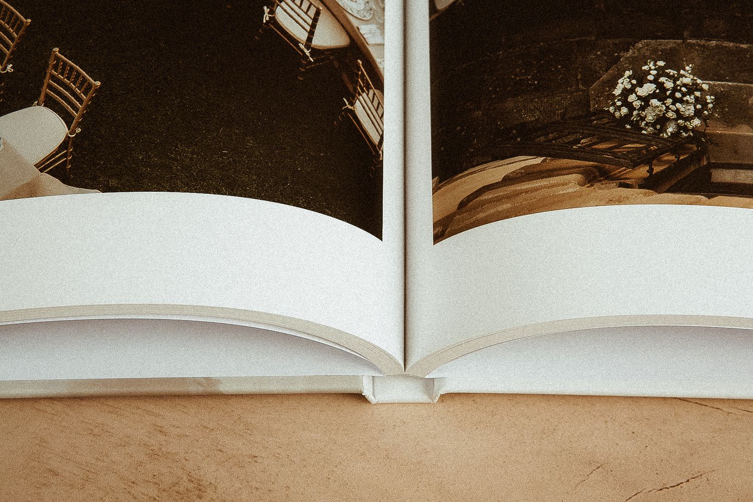 Close up view of an open photo album or wedding book with cream pages against a beige background.