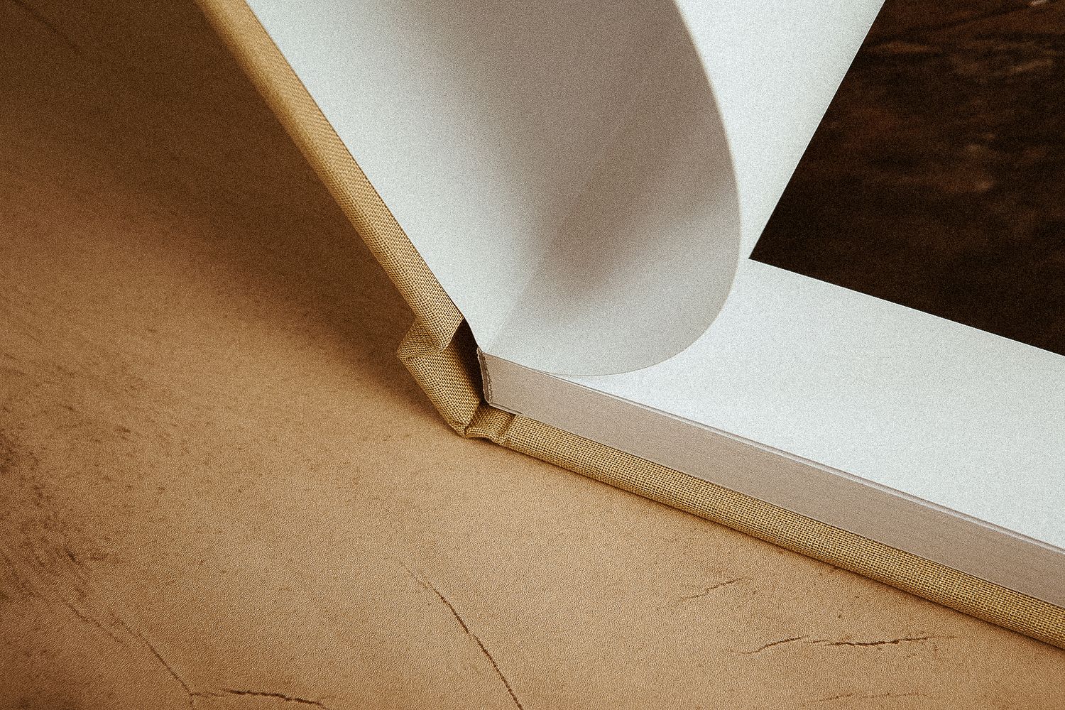 Close-up view of white paper curving over a beige surface creating an abstract minimalist composition.