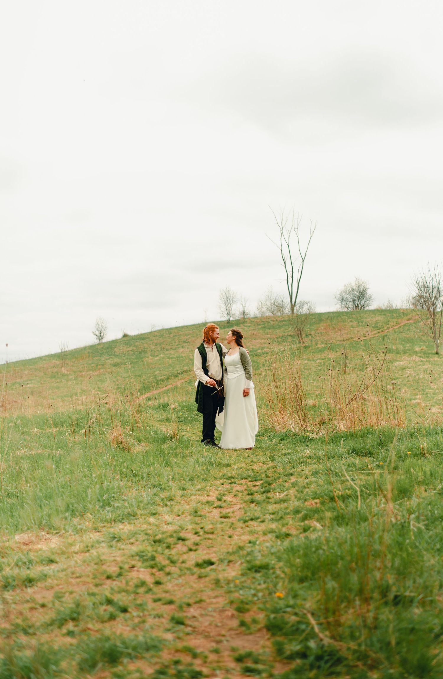 Bride and groom admiring eachother in a cloudy forest clearing.
