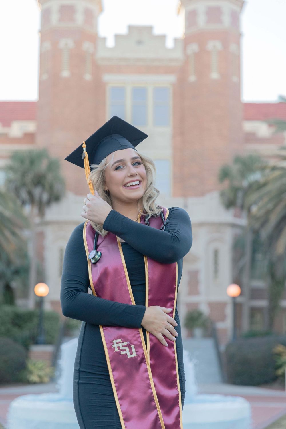 FSU graduation photo featuring a graduate in cap and gown with burgundy and gold stole in front of historic campus building.