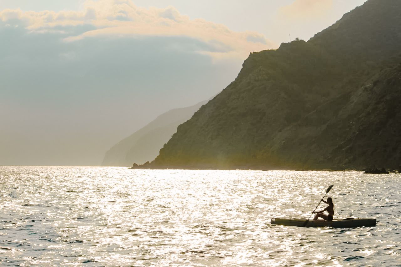 Dramatic seascape with dark mountain silhouette against shimmering water.