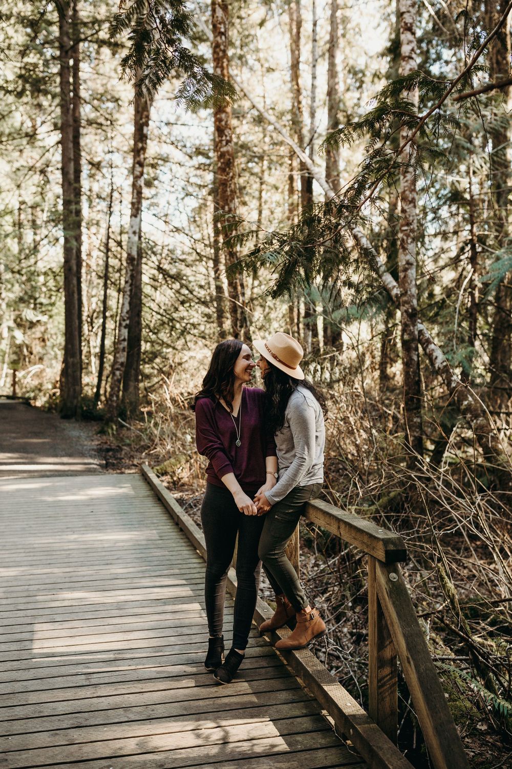 Two friends enjoying a beautiful autumn day on a wooden boardwalk path through a sunlit forest.