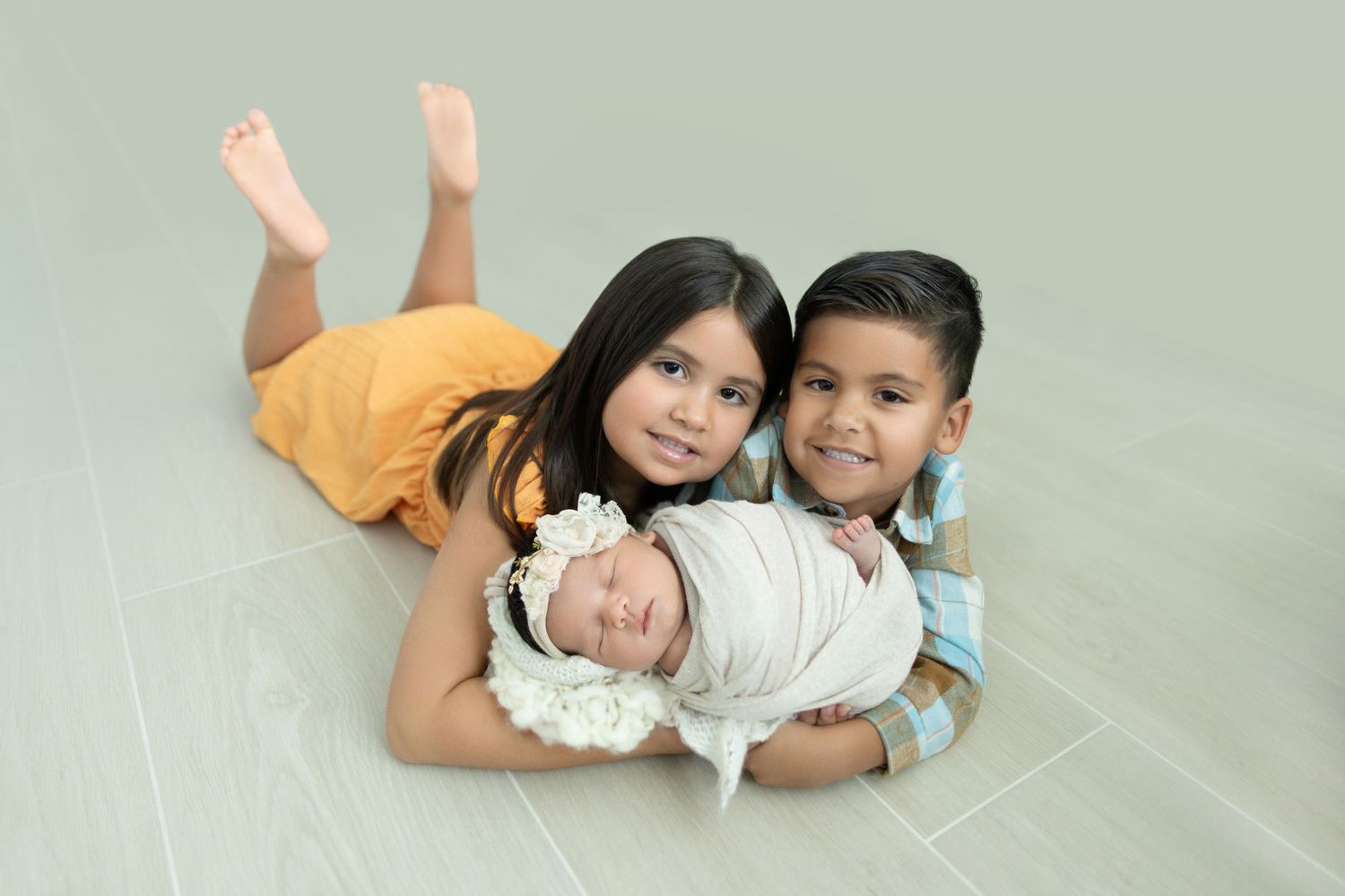 Family laying together on light green background during studio portrait session. Photos by Tampa Photographer DigitalMyst Photography
