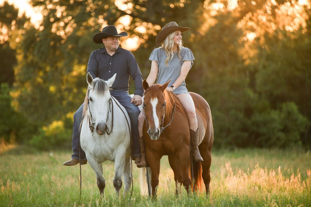 cowboy and cowgirl sitting on horses bareback in a backlit pasture