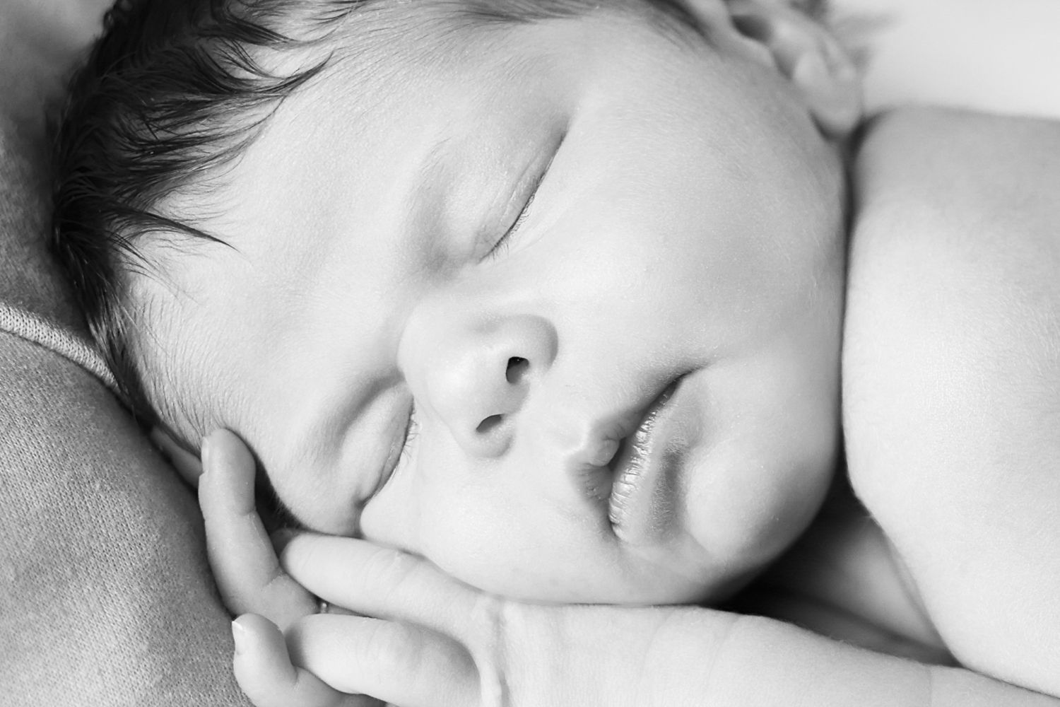 Close up black and white portrait of peaceful sleeping baby with hand resting near face. Carlsbad Roswell Artesia Hobbs New Mexico NM