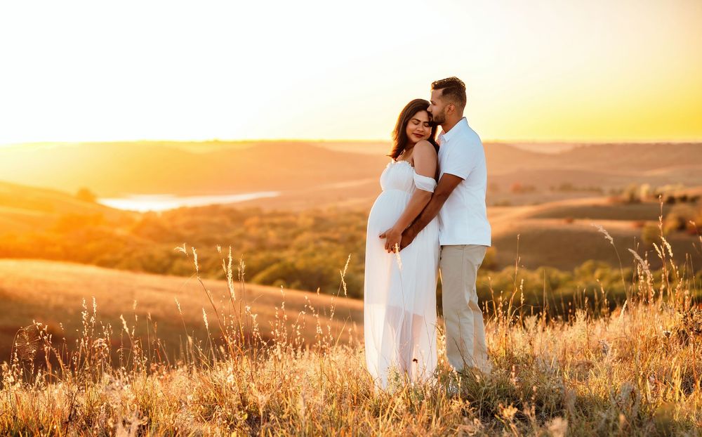 Silhouettes of a couple embrace in a golden wheat field during sunset creating a romantic summer scene.