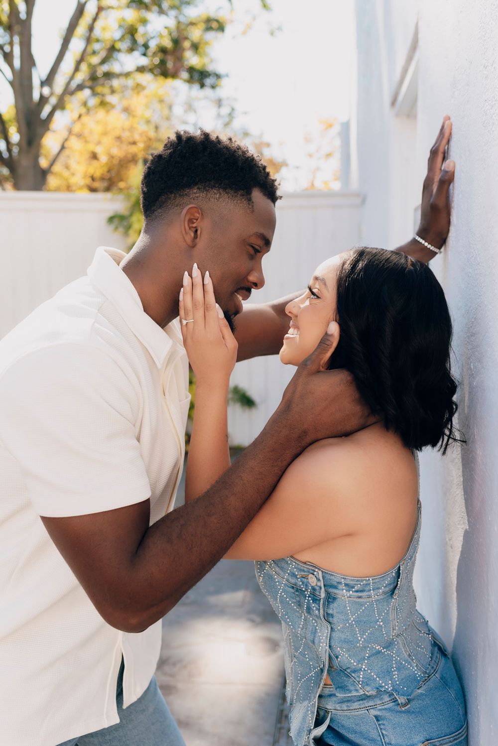 A romantic couple sharing an intimate moment against a white wall in warm sunlight. Dallas Engagement session, Dallas wedding photographer
