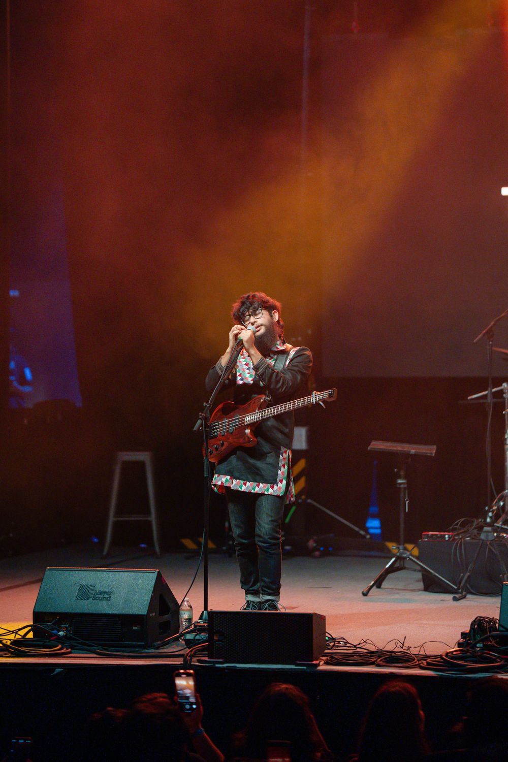 A musician plays guitar on stage during a concert with dramatic lighting.