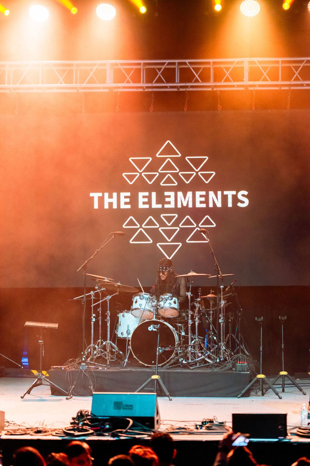 An empty stage set up for The Elements band with orange lighting and drum kit visible.