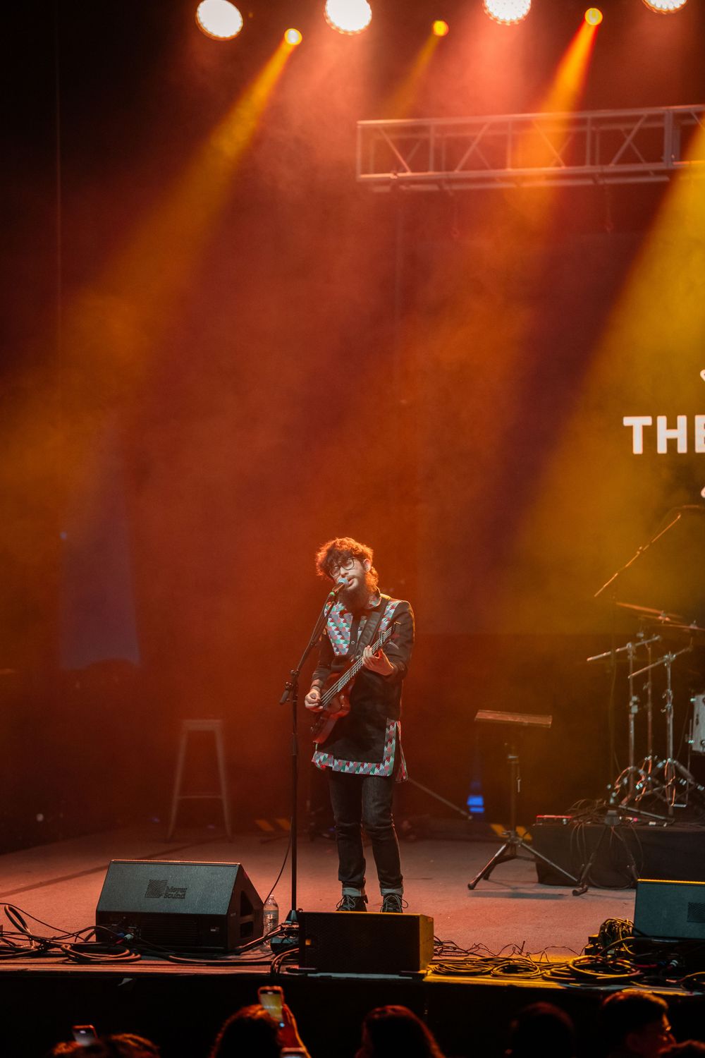 Concert performer on stage bathed in dramatic orange and yellow lighting during live show.