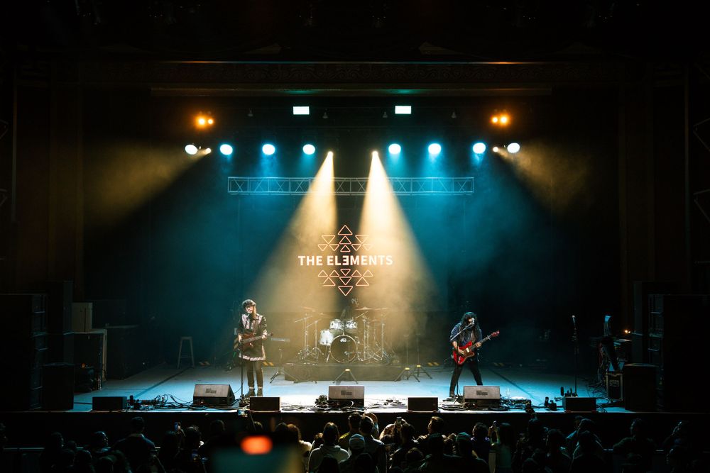 Band performing on stage with blue and amber spotlights creating atmospheric lighting effects.