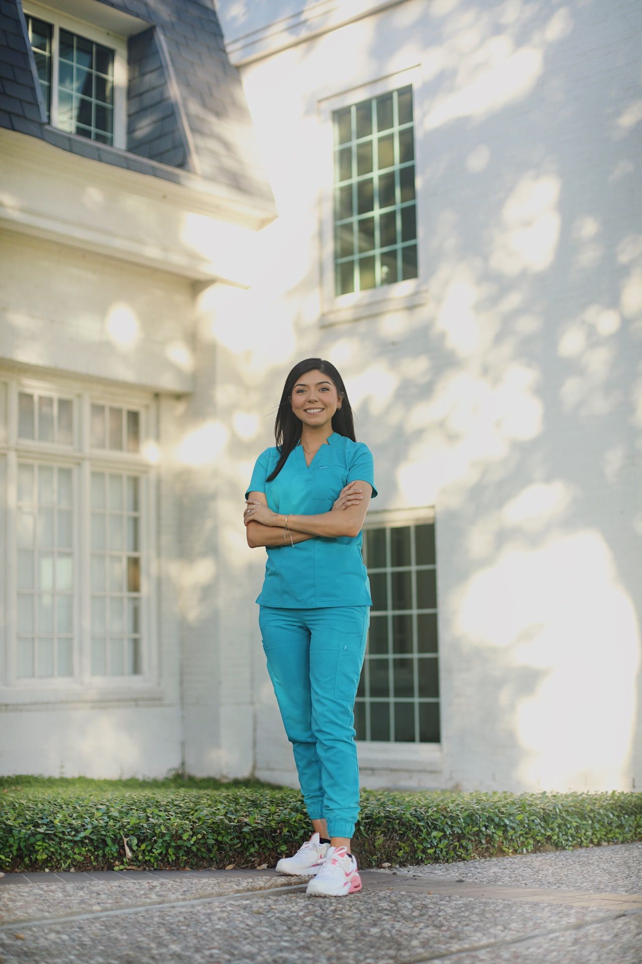 Graduate student crossing her arms behind a building.