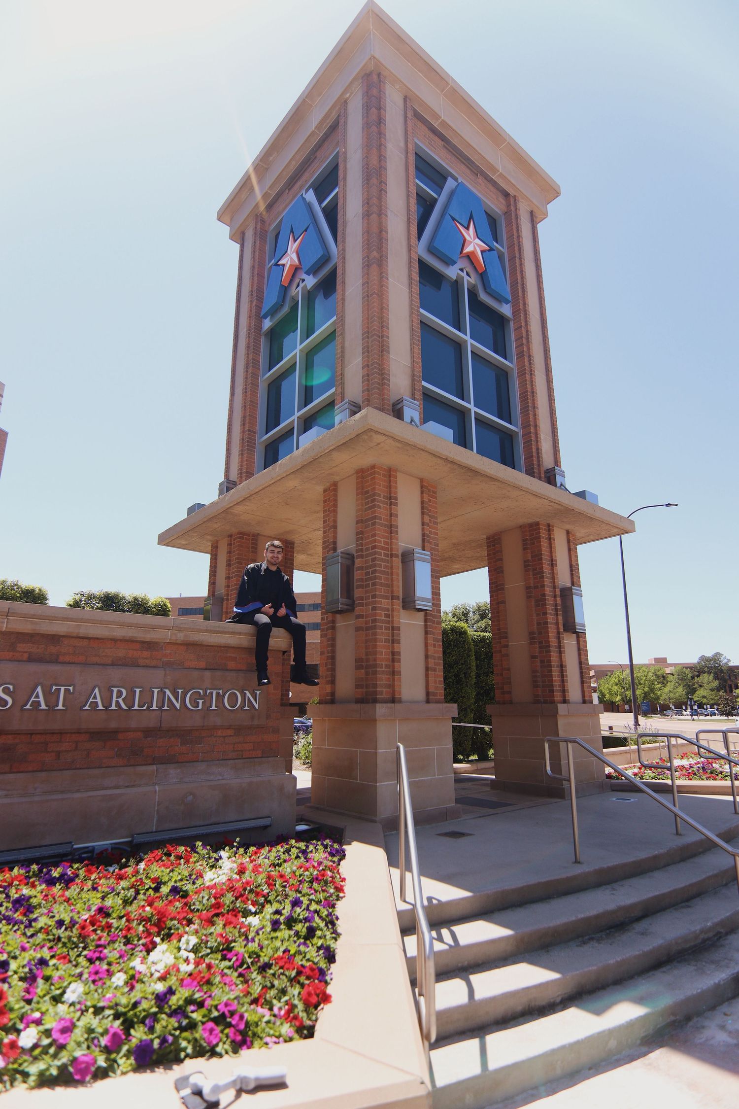 Graduate student sitting on a ledge and smiling.