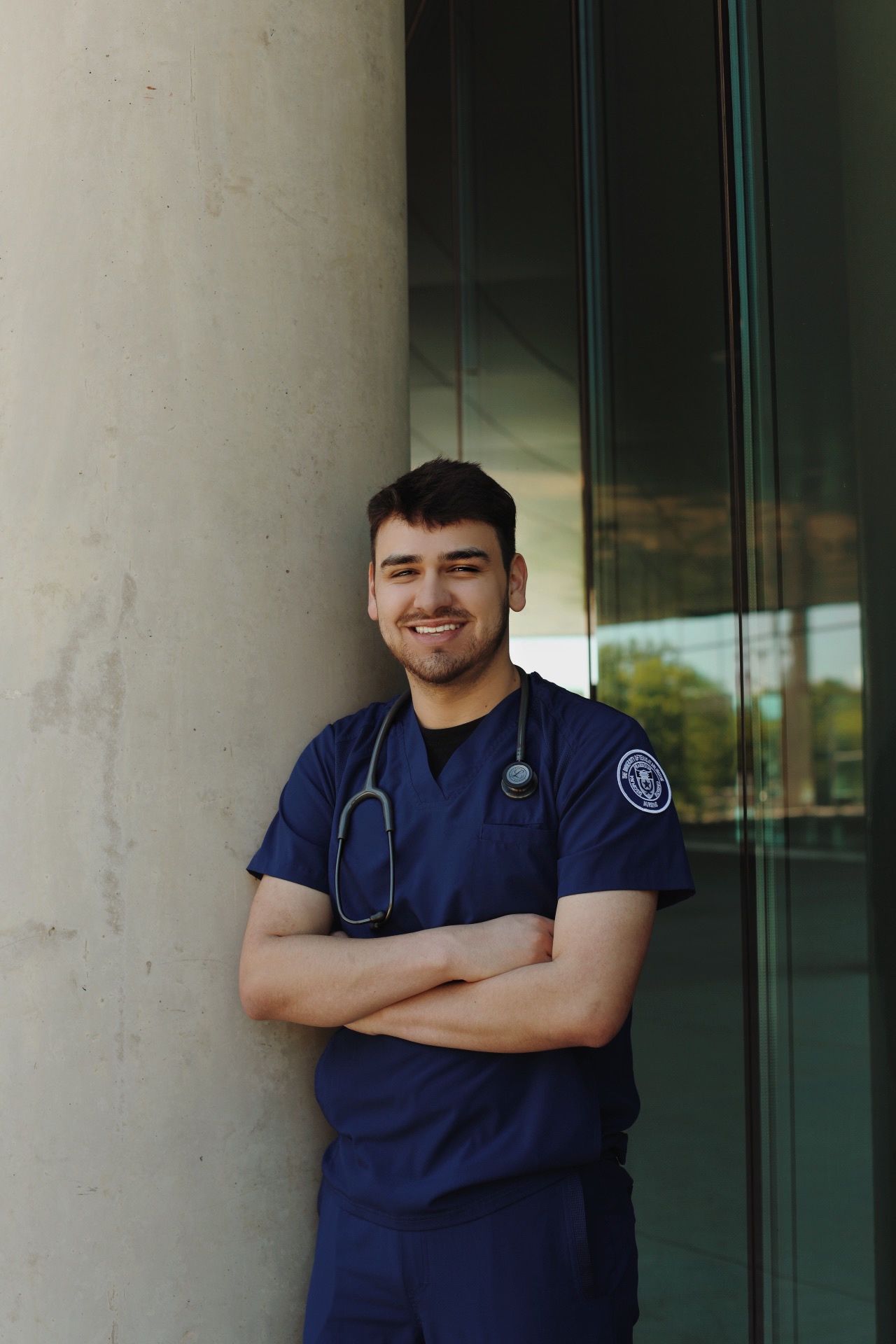 Student crossing his arms in scrubs.