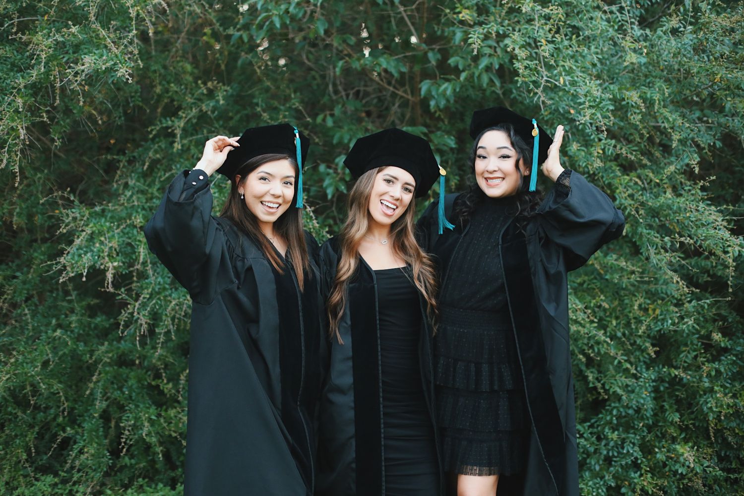 Three graduate students smiling and posing.