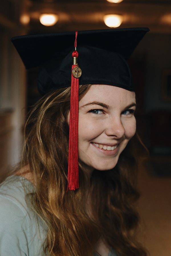 Woman smiling with graduation hat and red tassel.