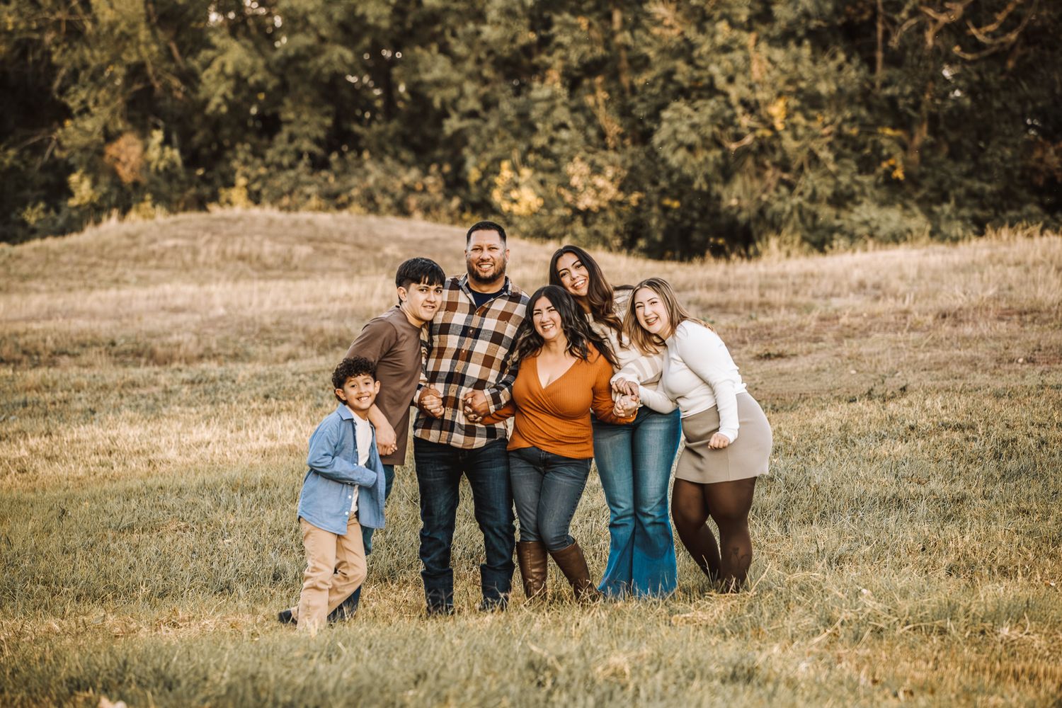 A family of 6 smiling for family pictures in Evans Colorado. Liz Rivas with Illuminating Images photography