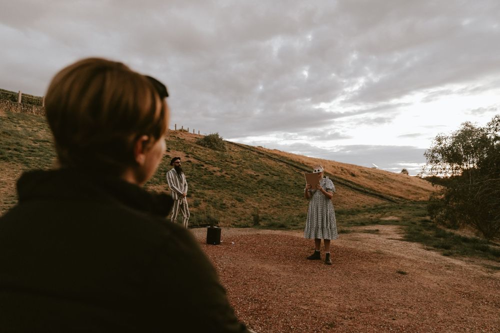 People filming a scene on a desert hillside during overcast weather.