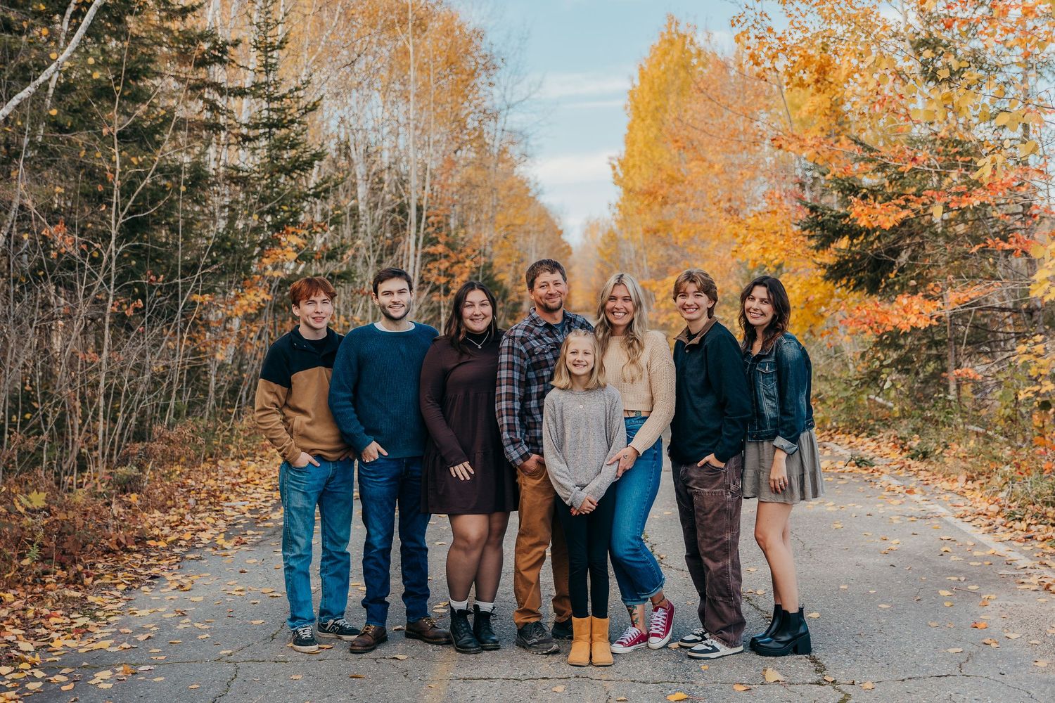 Family posing on path surrounded by vibrant fall foliage.