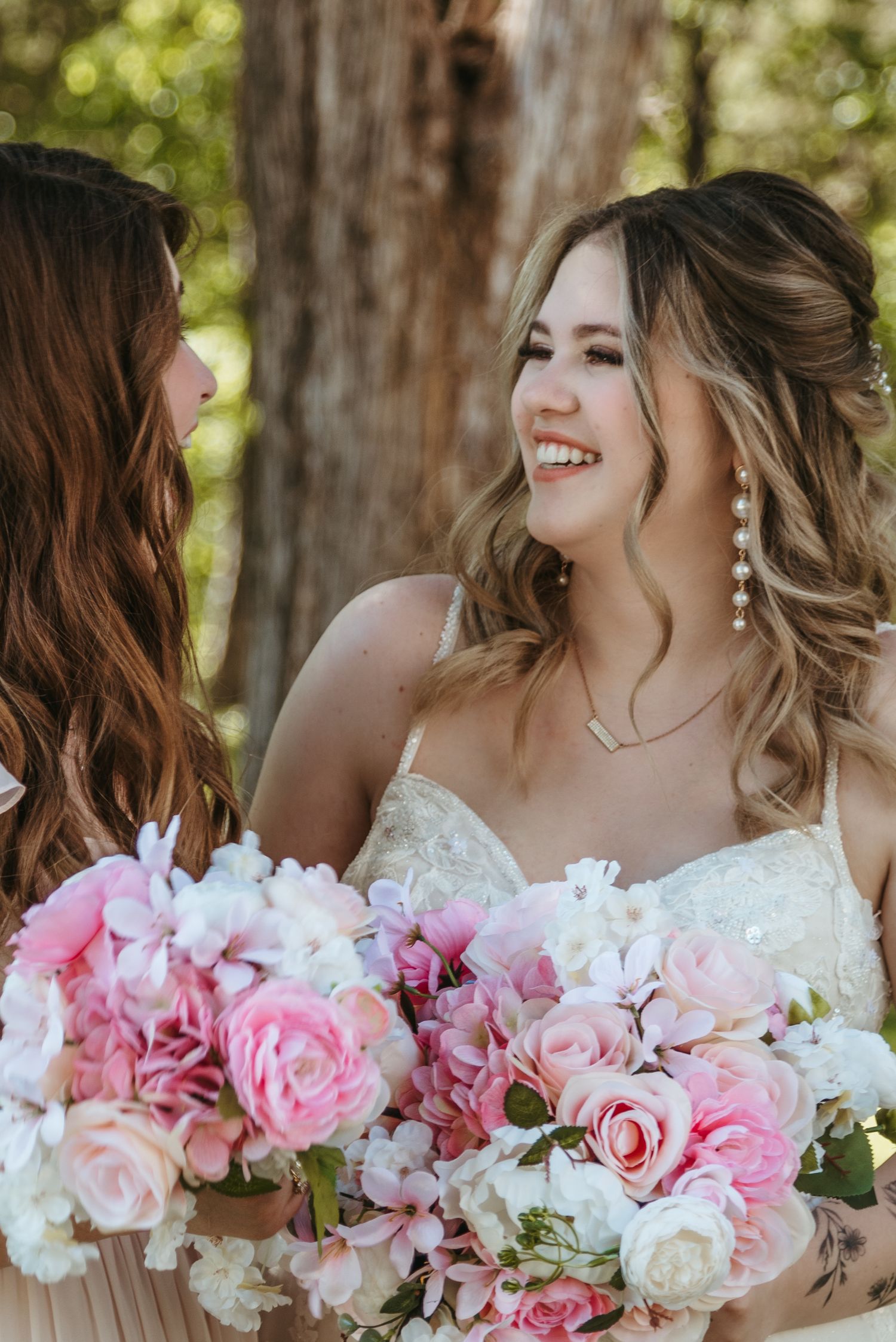 Two people share joyful moment with pink and white wedding bouquets.