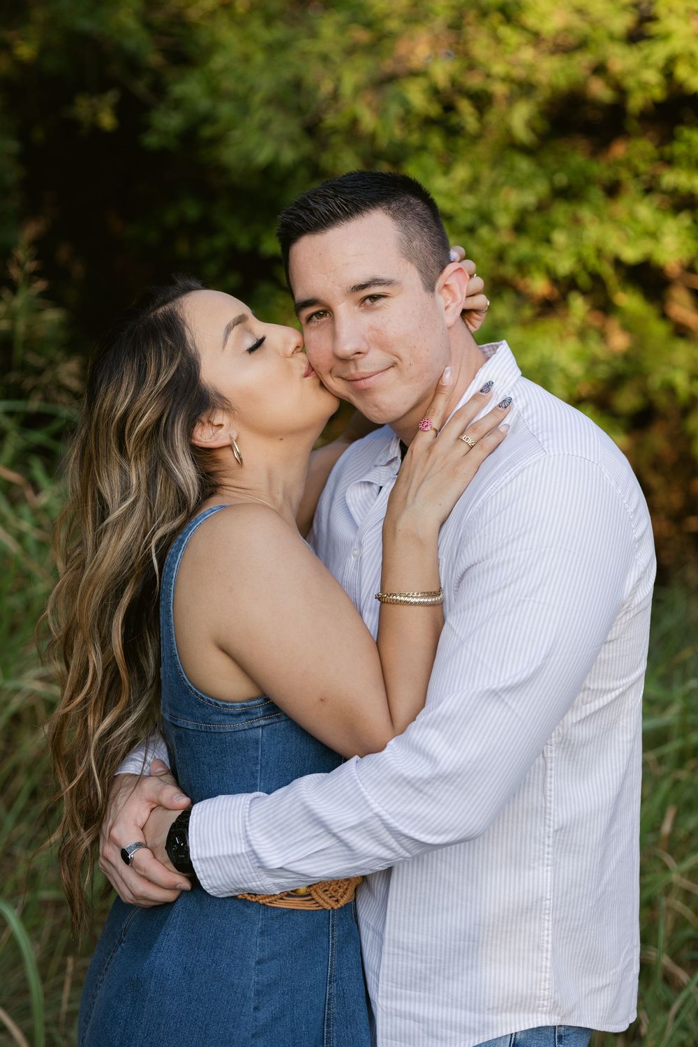 A couple shares intimate moments in a series of romantic outdoor photos with autumn foliage in the background.