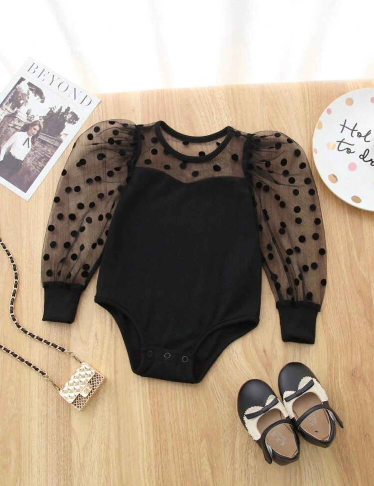 Black polka dot mesh sleeve bodysuit with matching accessories laid flat.