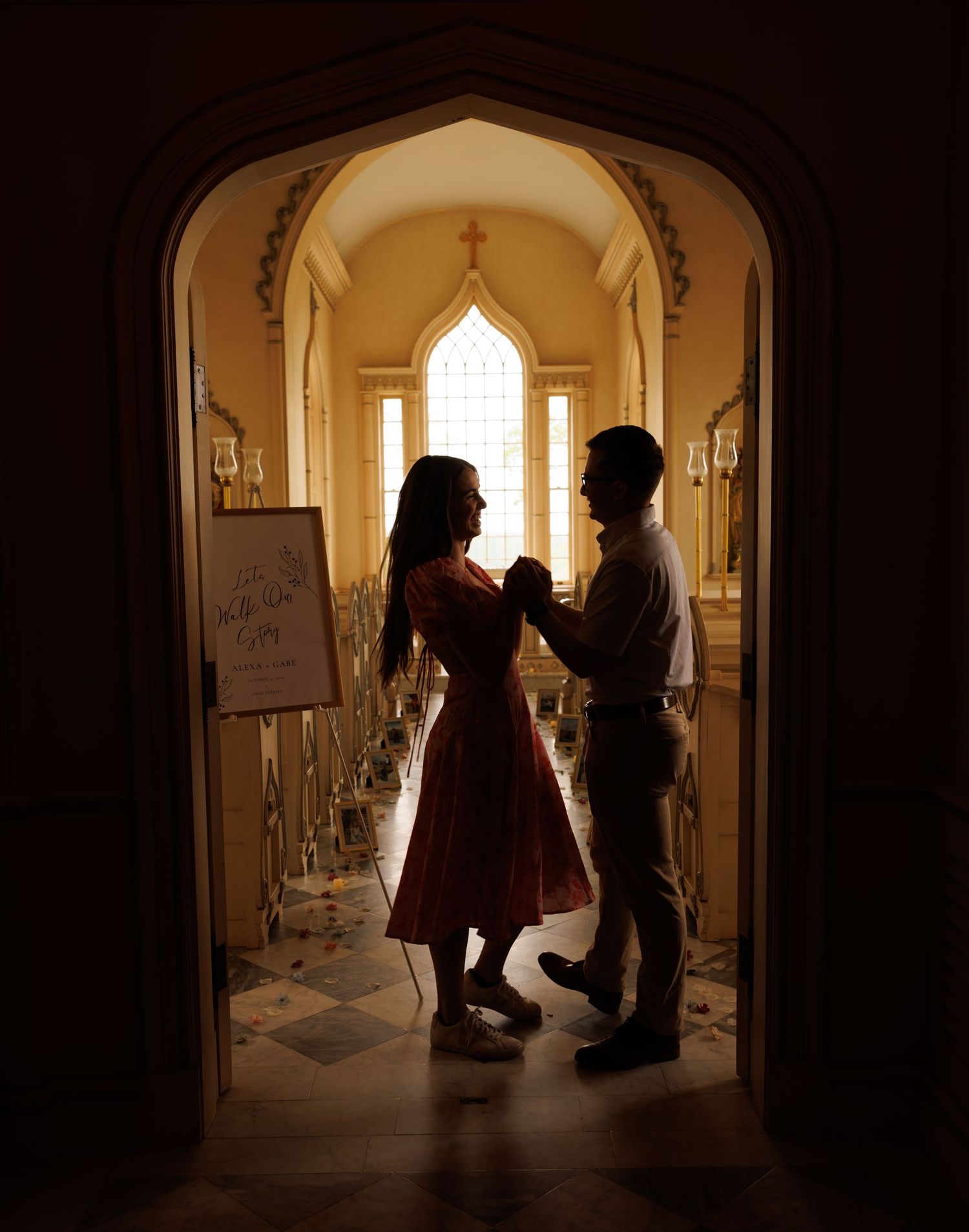 Two silhouettes stand in a romantic arch doorway with sunlight streaming through a Gothic window behind them.