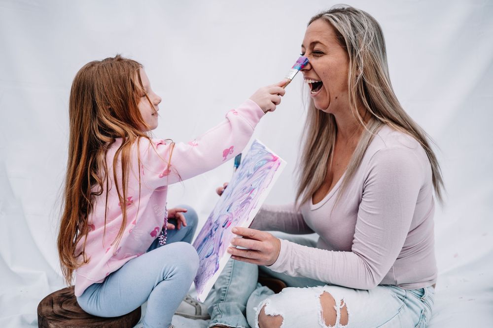 A mother and daughter playing together with a toy unicorn stick, sharing a fun and playful moment.