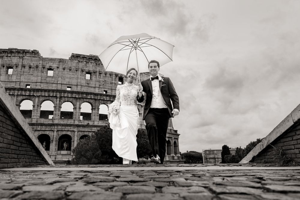 A romantic wedding photo session captured near an ancient colosseum with dramatic cloudy skies.