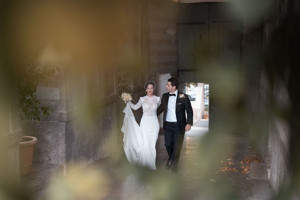 Wedding couple posing for romantic photos through lush foliage at an outdoor venue.
