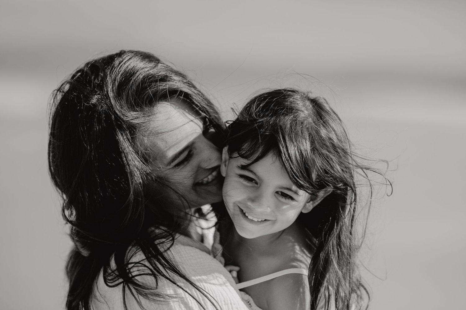 A tender moment captured in black and white shows a loving embrace between two people with windswept hair.