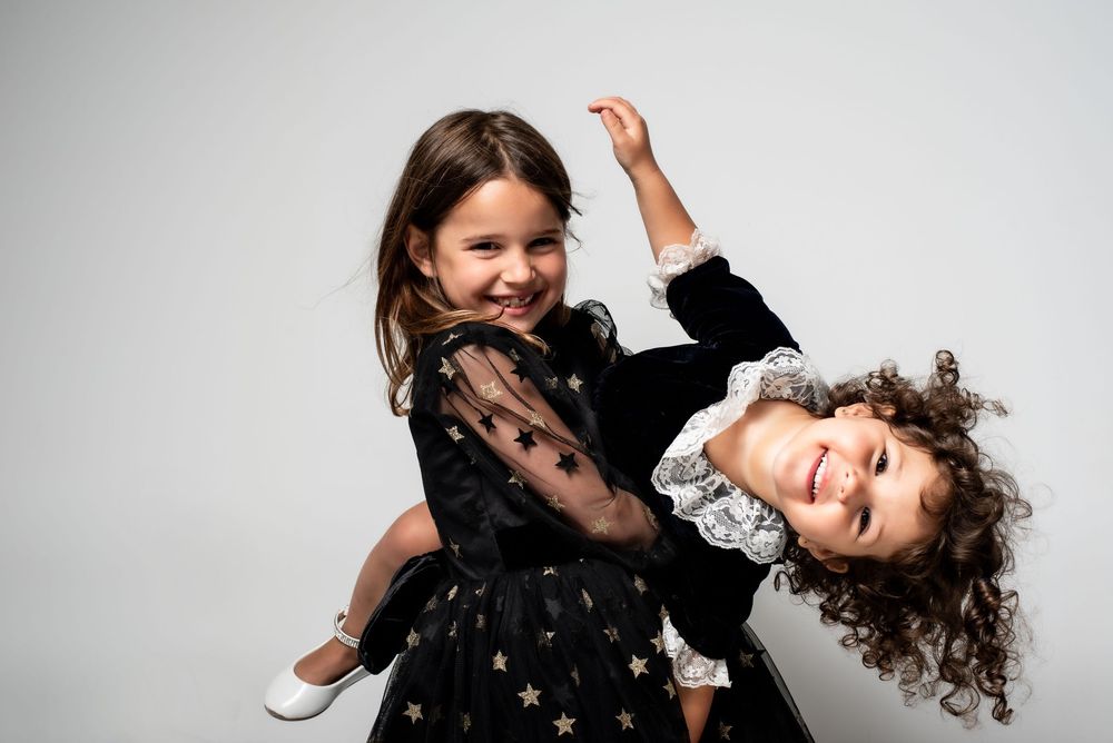 Fine art studio portrait of two sisters in matching dresses.