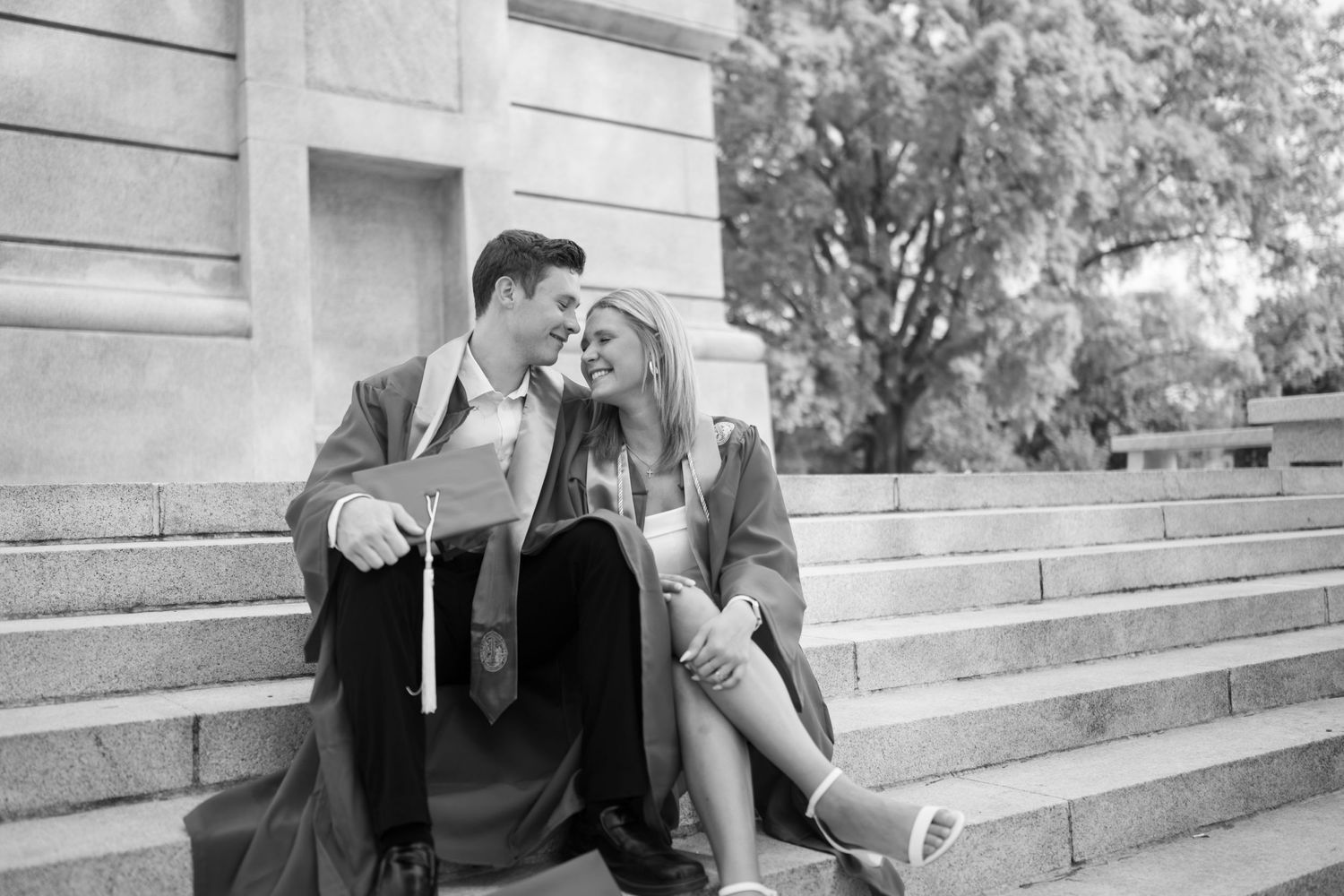 A couple sharing a laugh while sitting on stone steps in black and white.