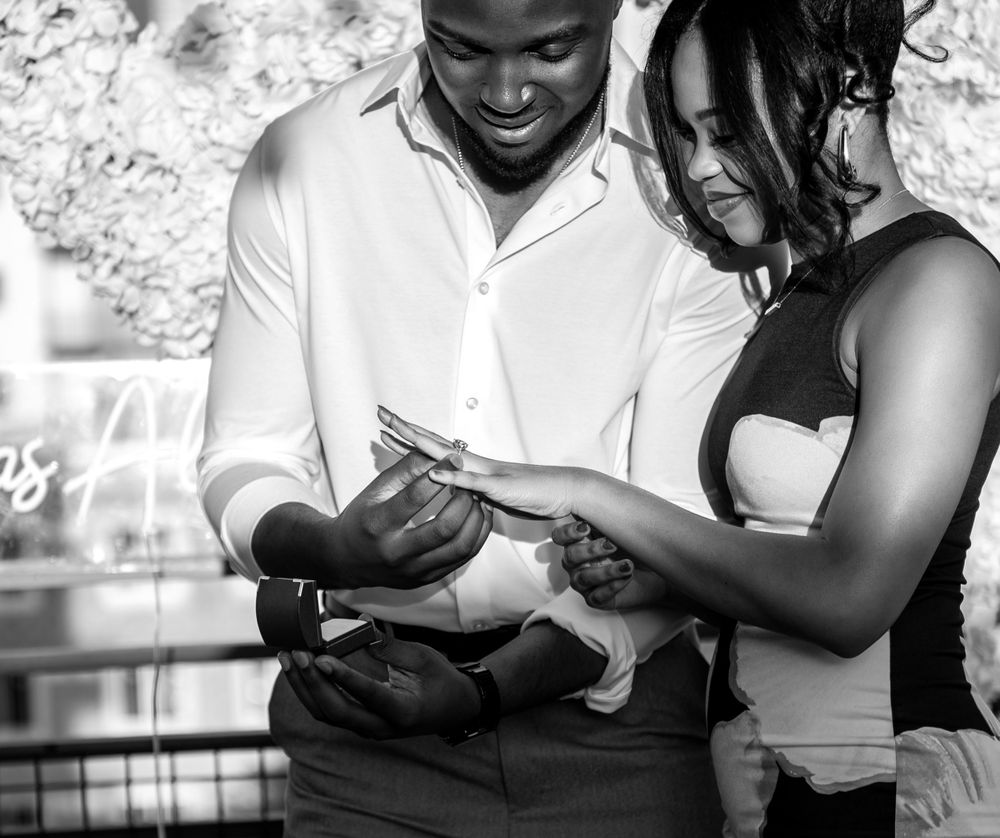 Fiancés stare earnestly at the engagement ring on the bride-to-be's finger. The moment was captured by proposal photographers in Florida.