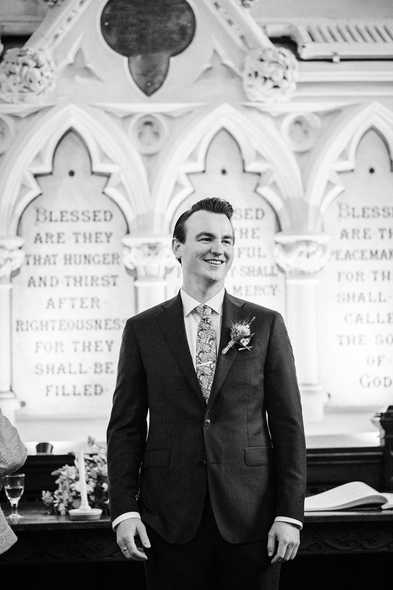 A joyful moment captured in black and white at a church wedding ceremony with ornate Gothic architecture in the background.