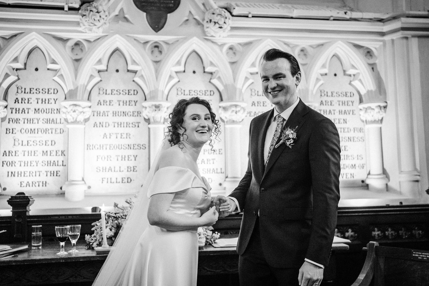 A vintage black and white photo of a joyful wedding moment captured inside an ornate church with decorative arches.