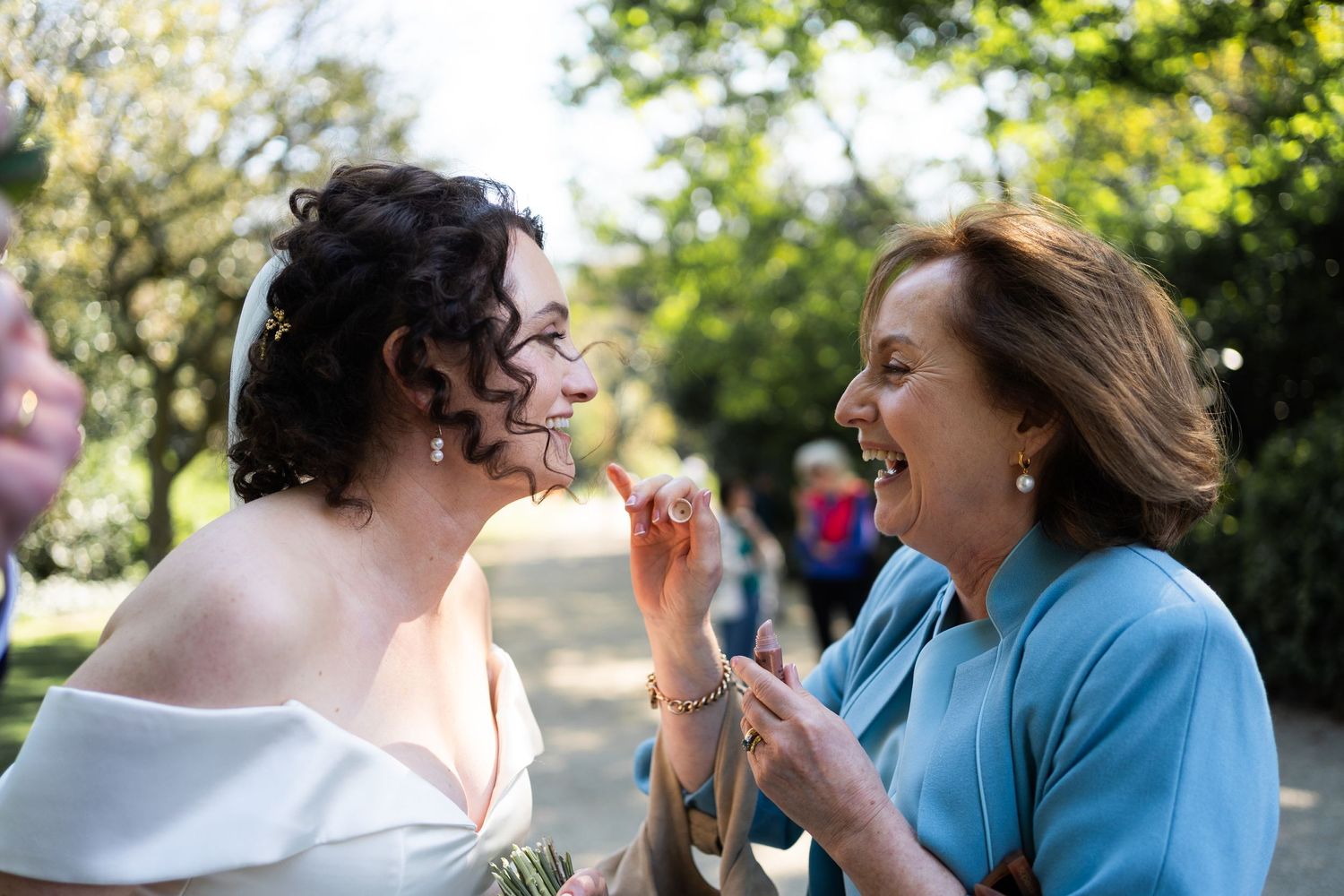Two people sharing a joyful moment while laughing together outdoors in a garden setting.