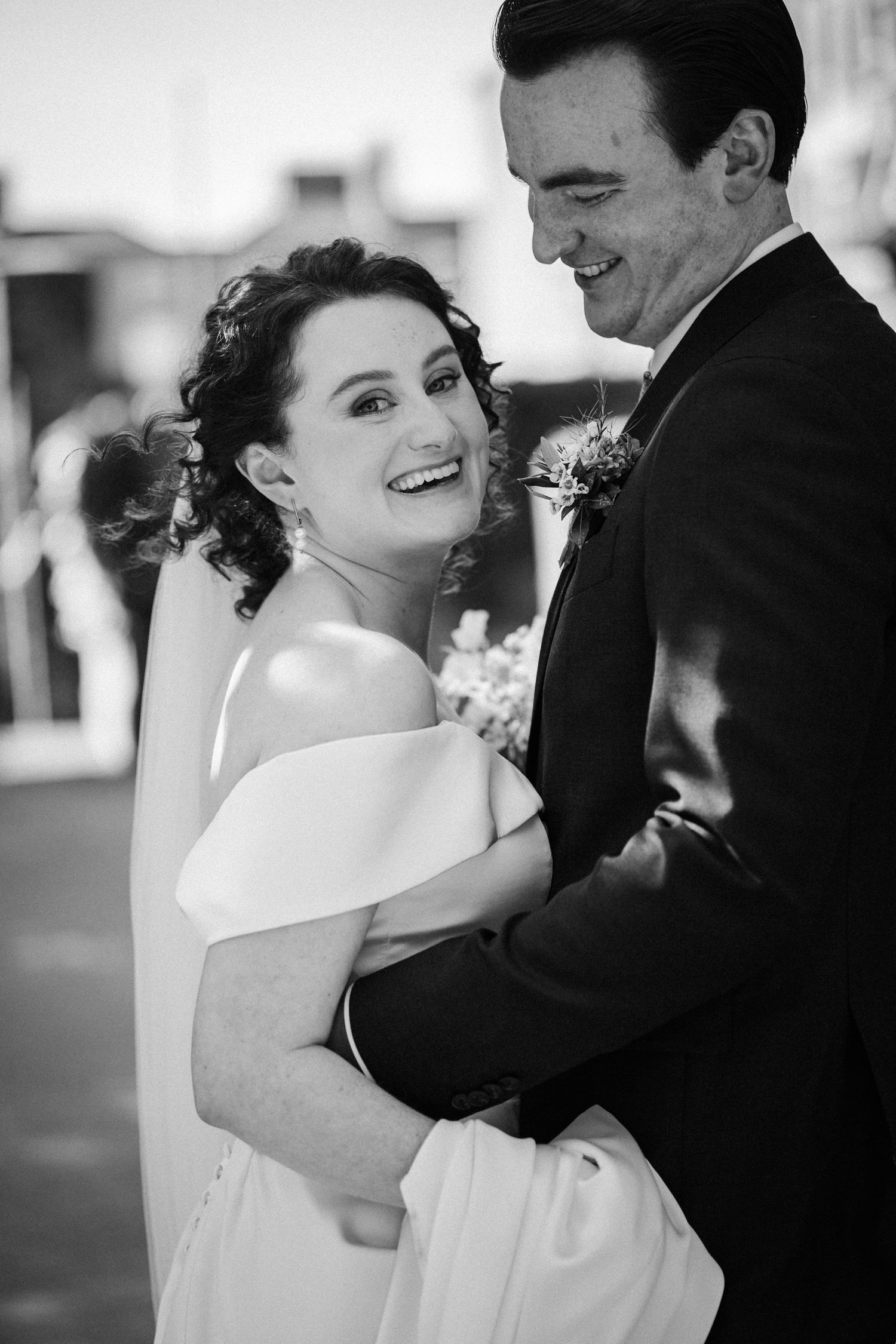 Black and white wedding photo of a joyful bride and groom sharing an intimate candid moment while dancing together.