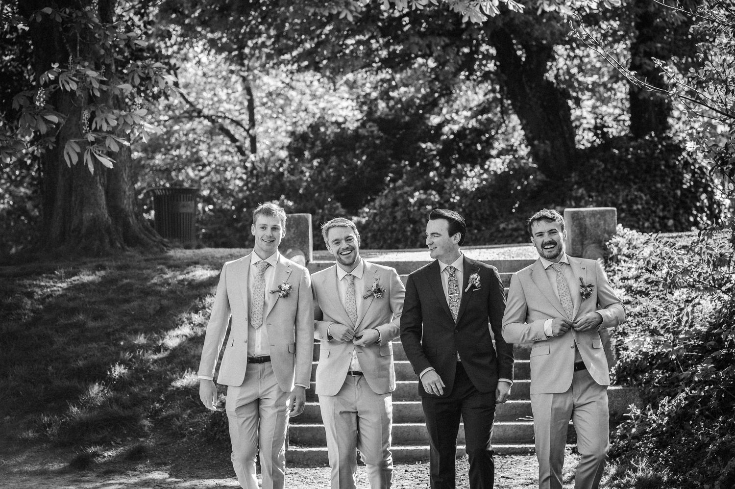 Four smartly dressed people walk together on garden steps in a black and white vintage photograph.