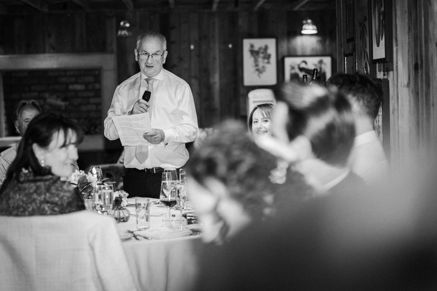 A server stands at attention in an elegant restaurant dining room while taking orders at a formal table setting.
