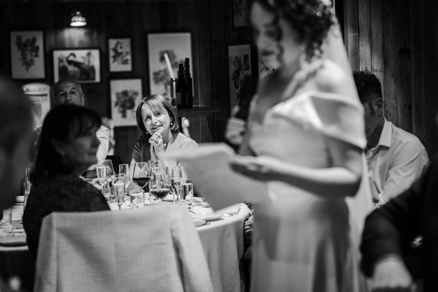 Black and white photograph showing guests seated at elegant tables during an intimate restaurant dinner gathering.
