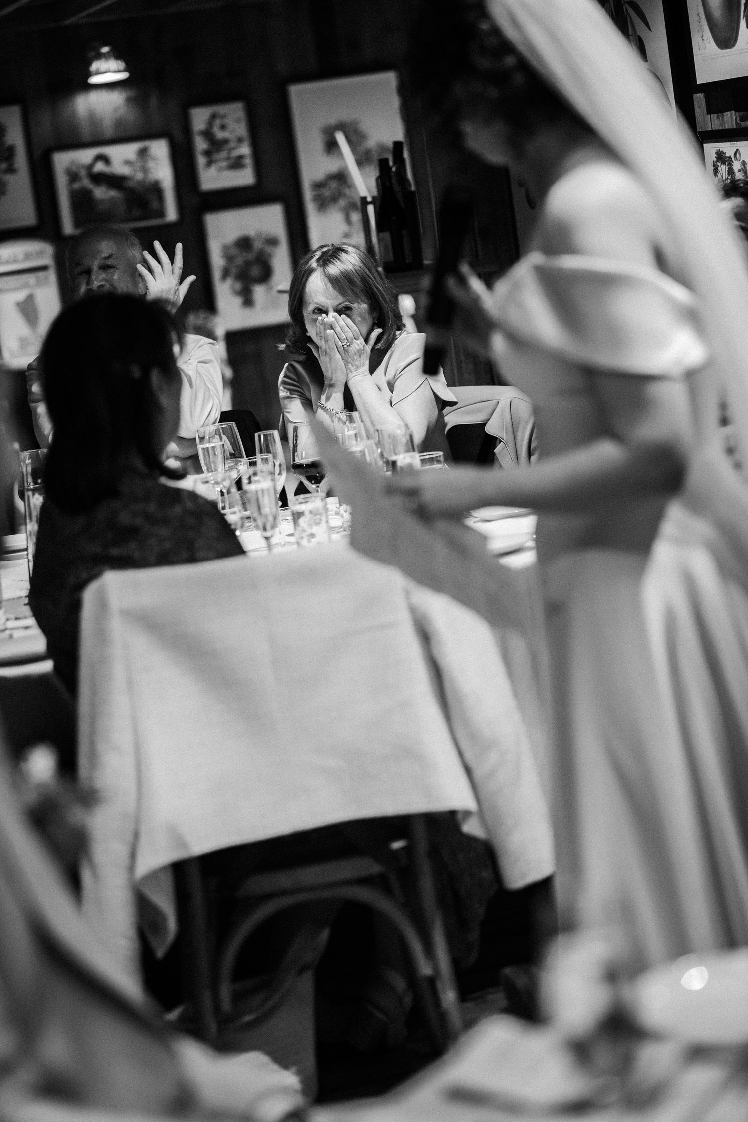 Guests engaged in conversation at a restaurant table with vintage artwork adorning the walls in black and white.